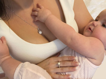 Woman Wearing Breast Milk Ring and Necklace Set while Holding Baby - KeepsakeMom
