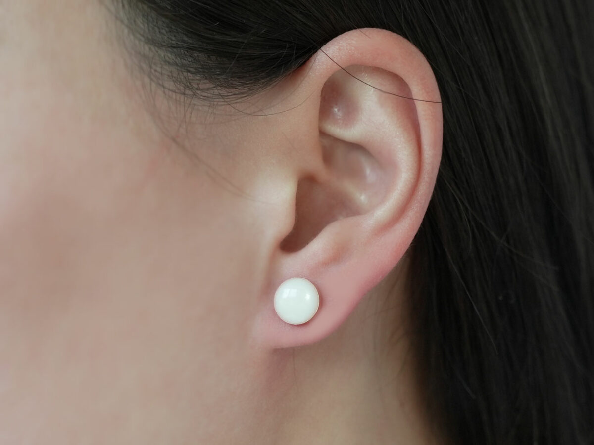 breastmilk jewelry earrings on a model ear from KeepsakeMom round simple studded
