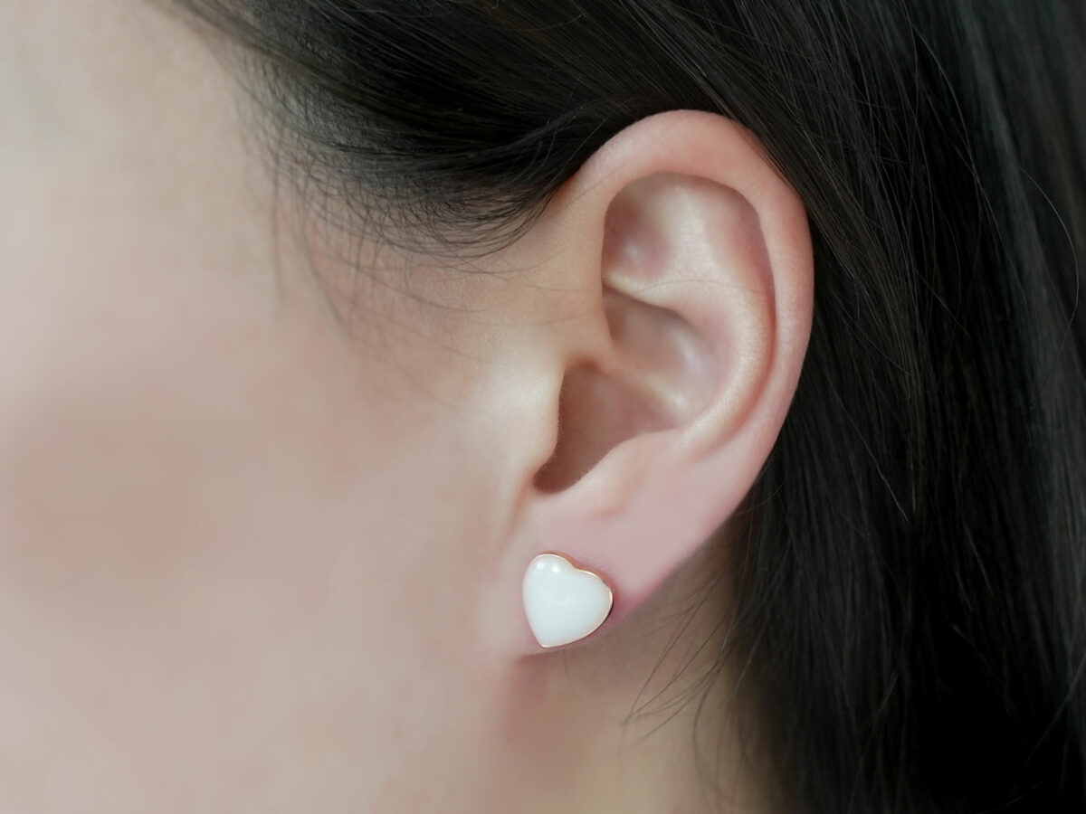 breast milk studded earring in rose gold heart shaped from keepsakemom on a model ear