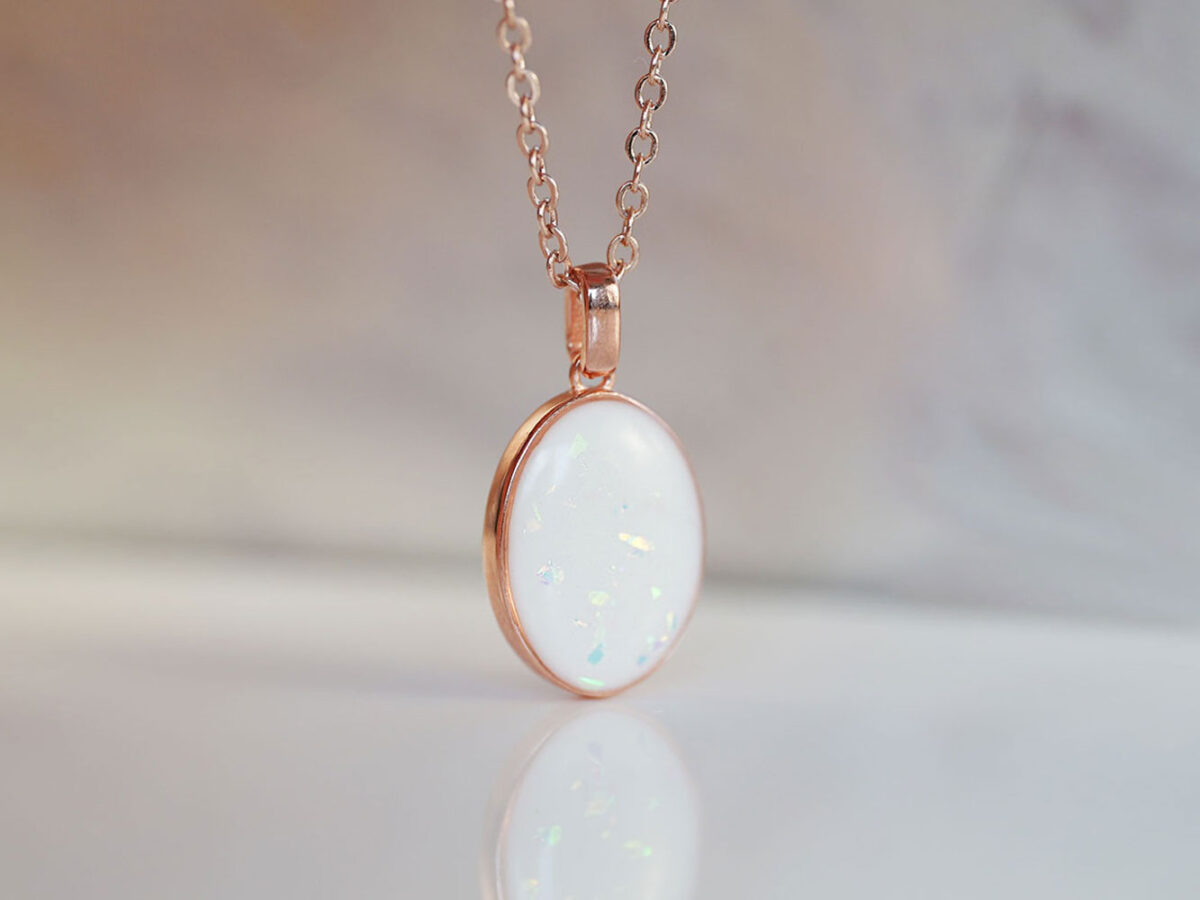 breastmilk jewelry oval simple necklace from keepsakemom in rose gold setting on light background with opal flakes in milk stone