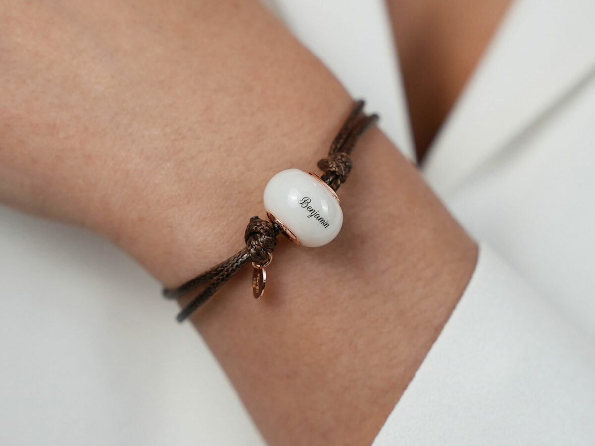 breastmilk jewelry bead brown cord bracelet with rose gold bead cores and tag with child's name on the bead engraved from KeepsakeMom on a model wrist