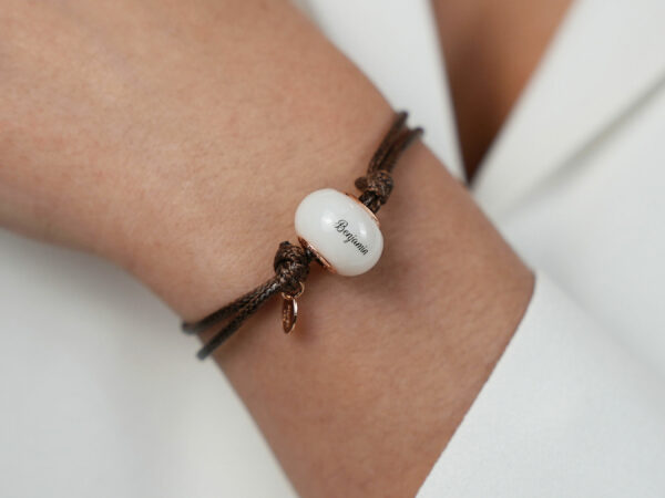 breastmilk jewelry bead brown cord bracelet with rose gold bead cores and tag with child's name on the bead engraved from KeepsakeMom on a model wrist