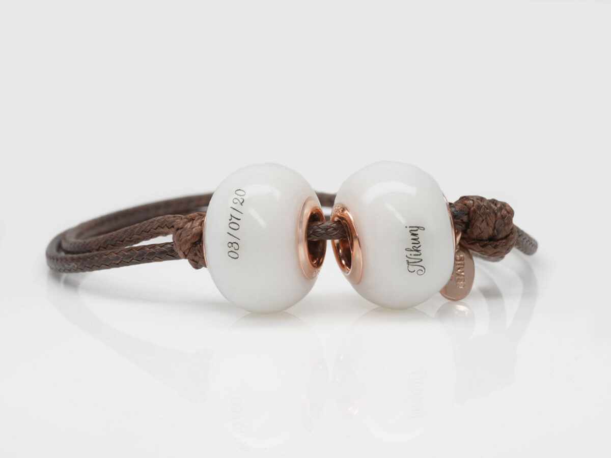 two breastmilk beads on a brown cord with children's names on white background from keepsakemom