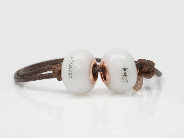 two breastmilk beads on a brown cord with children's names on white background from keepsakemom