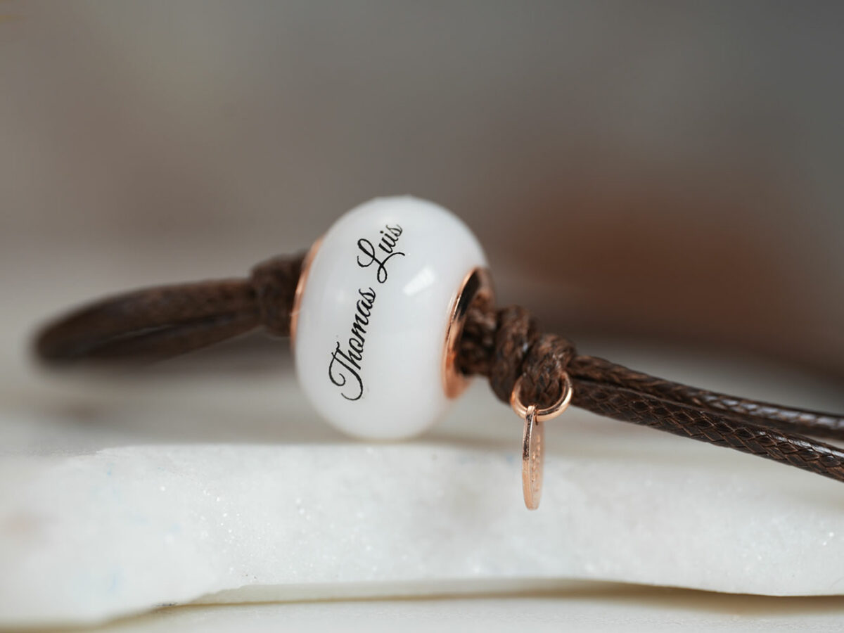 breastmilk jewelry bead brown cord bracelet with rose gold bead cores and tag with child's name on the bead engraved from KeepsakeMom