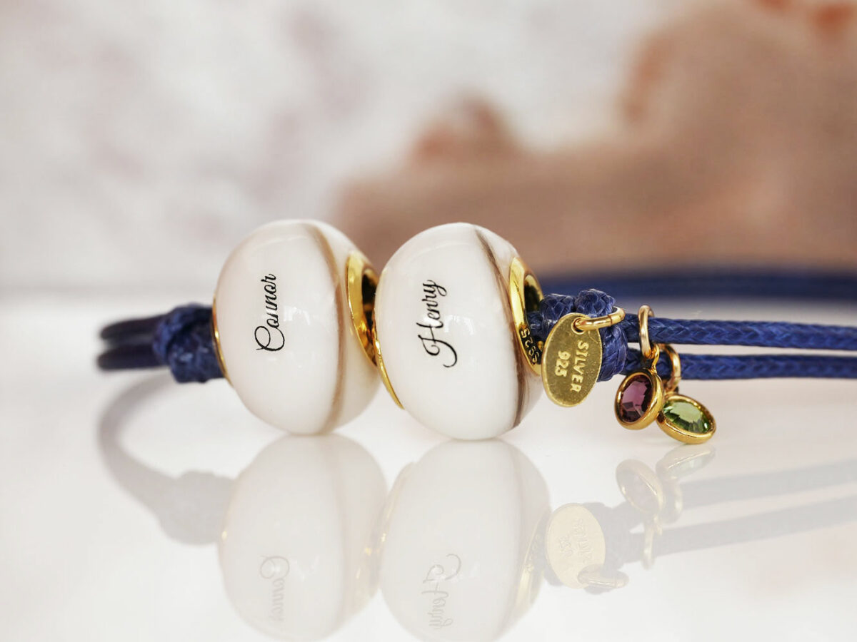 two breastmilk jewelry beads bracelet with yellow gold bead cores and navy blue waxed cord and birth color purple and green from KeepsakeMom