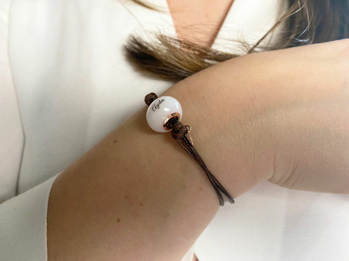 breastmilk jewelry bead brown cord bracelet with rose gold bead cores and tag with child's name on the bead engraved from KeepsakeMom on a model wrist