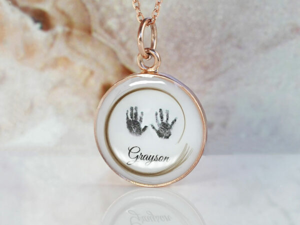breastmilk jewelry necklace disc with baby foot hand prints lock of hair and baby's name and rose gold chain from KeepsakeMom