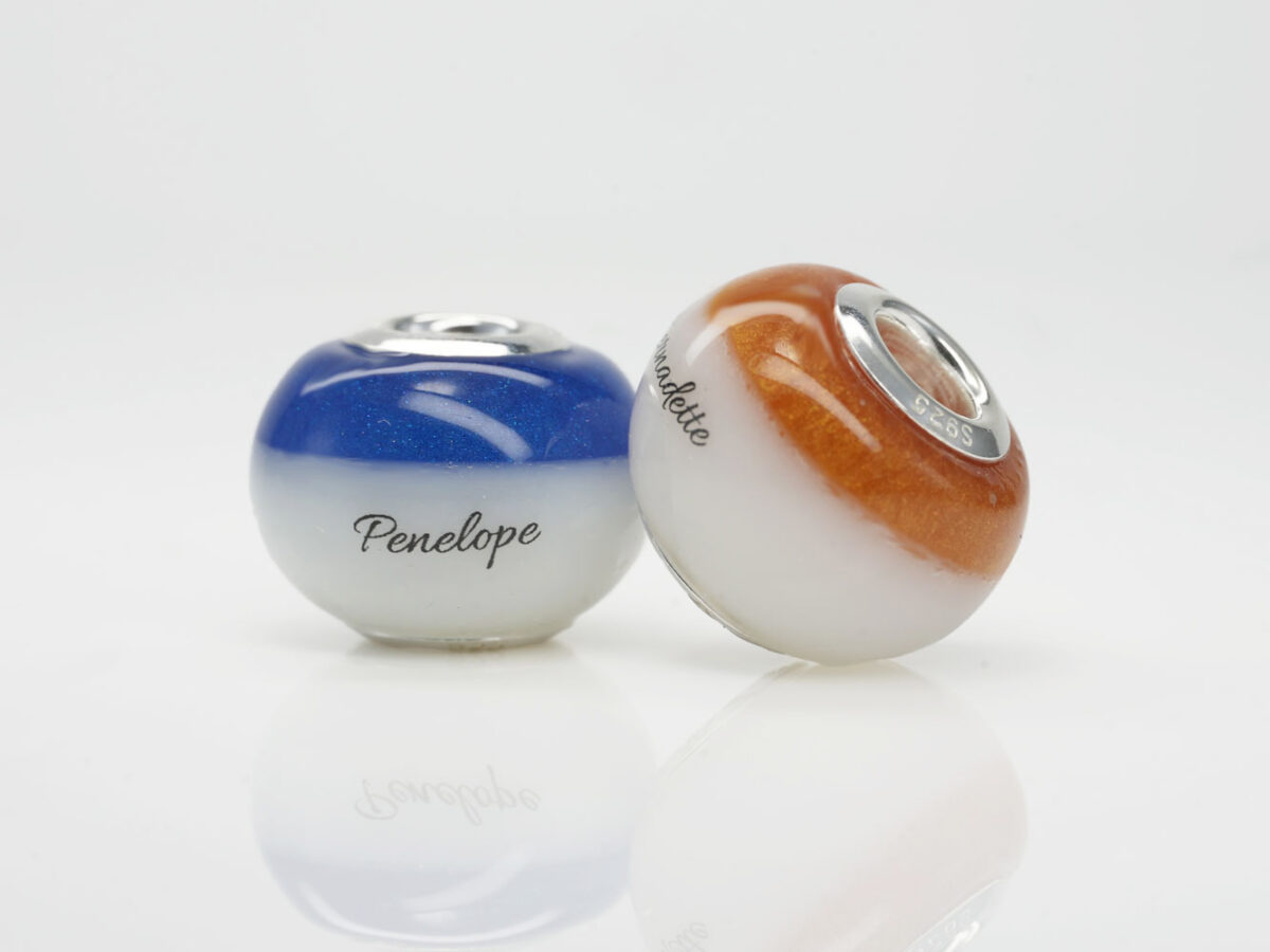 two beads with blue and orange birth month colors at the top with children's names from keepsakemom on white background