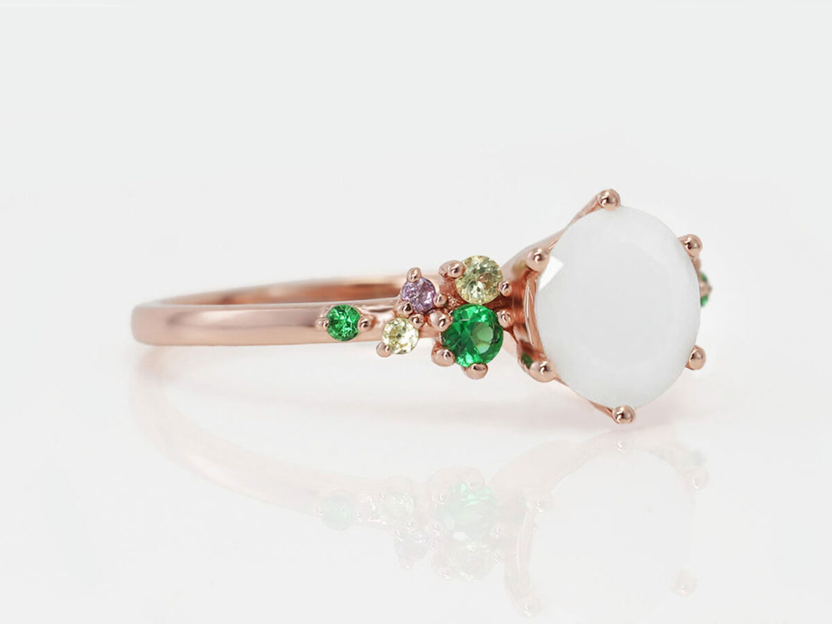 breast milk ring from keepsakemom with green gems on a side and diamond shaped breast milk central stone