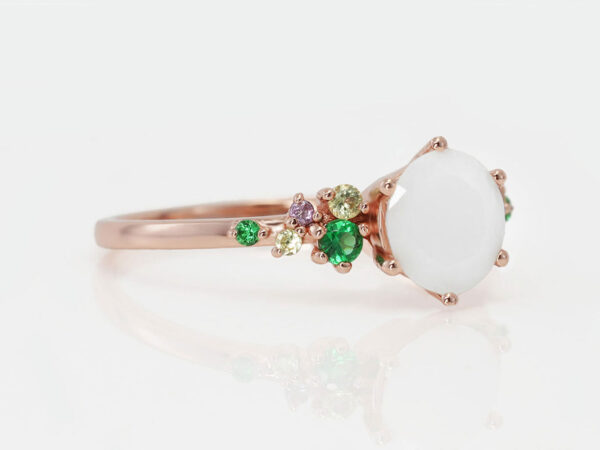 breast milk ring from keepsakemom with green gems on a side and diamond shaped breast milk central stone