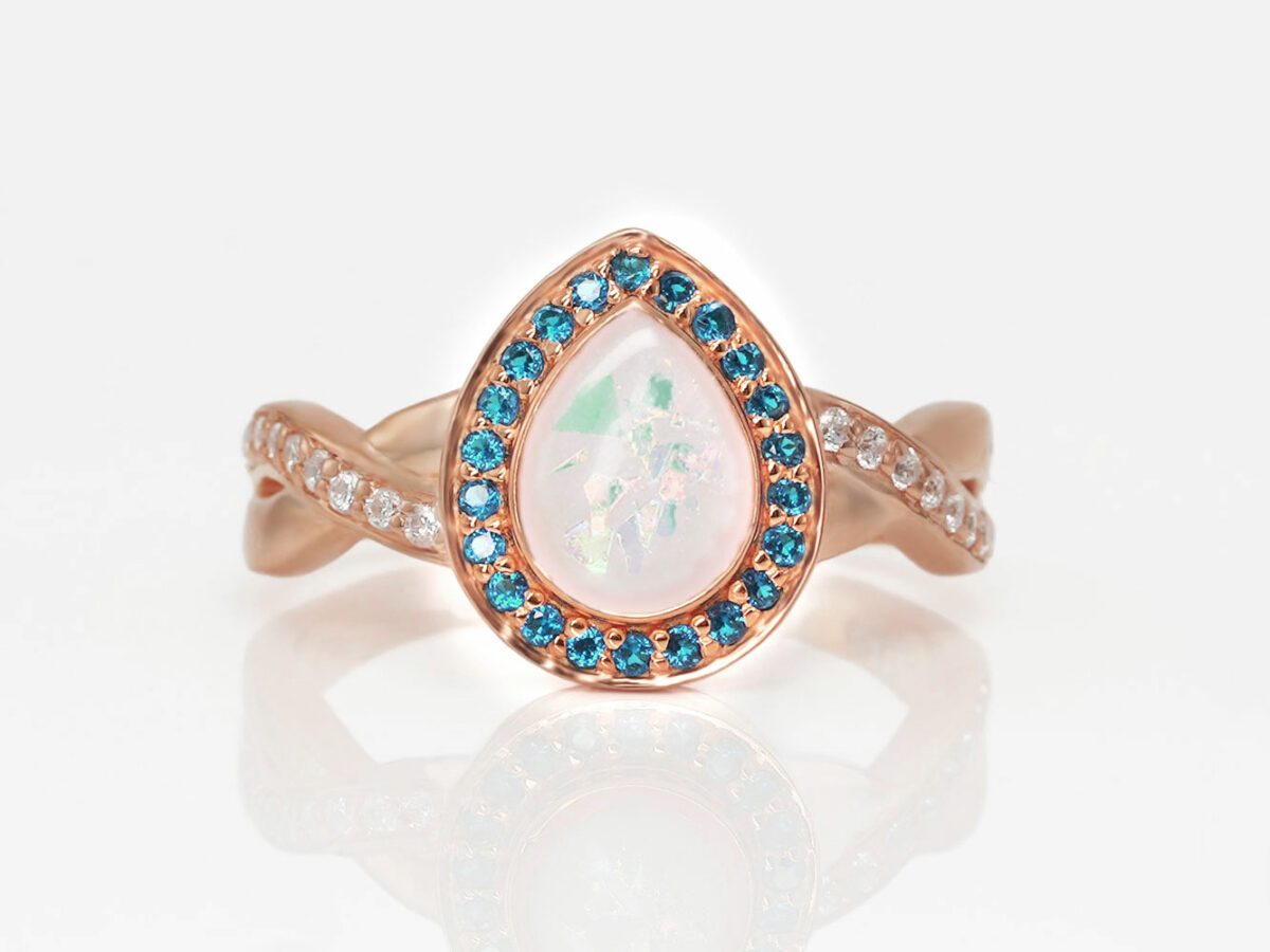 breastmilk jewelry ring rose gold teardrop blue crystal around the halo and clear crystals on the band with opal flakes keepsakemom