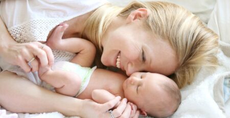 Happy mother snuggling in bed with baby