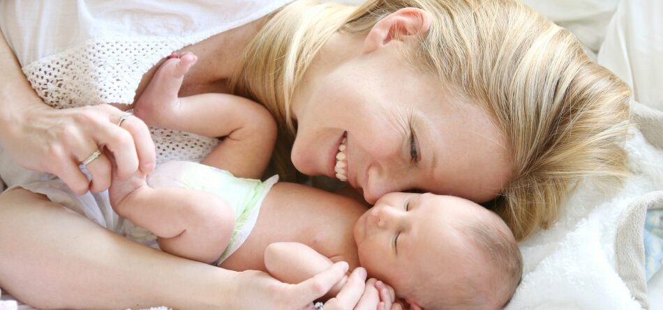 Happy mother snuggling in bed with baby