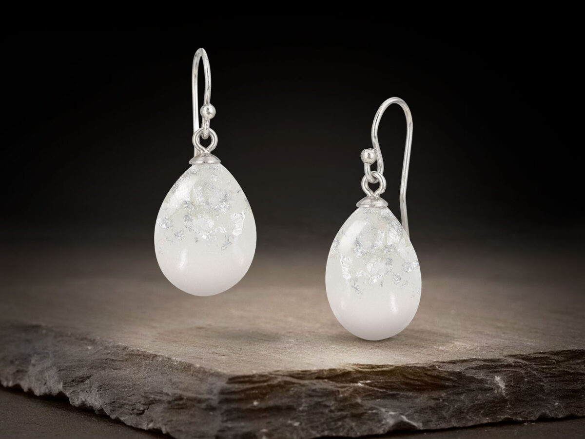 breastmilk jewelry drop or teardrop shaped earrings on a dark background hanging from KeepsakeMom with silver flakes and silver hooks