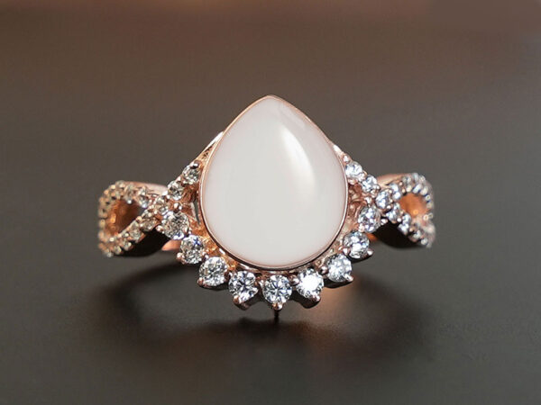 breastmilk jewelry ring clear crystals around teardrop from KeepsakeMom rose gold on brown background