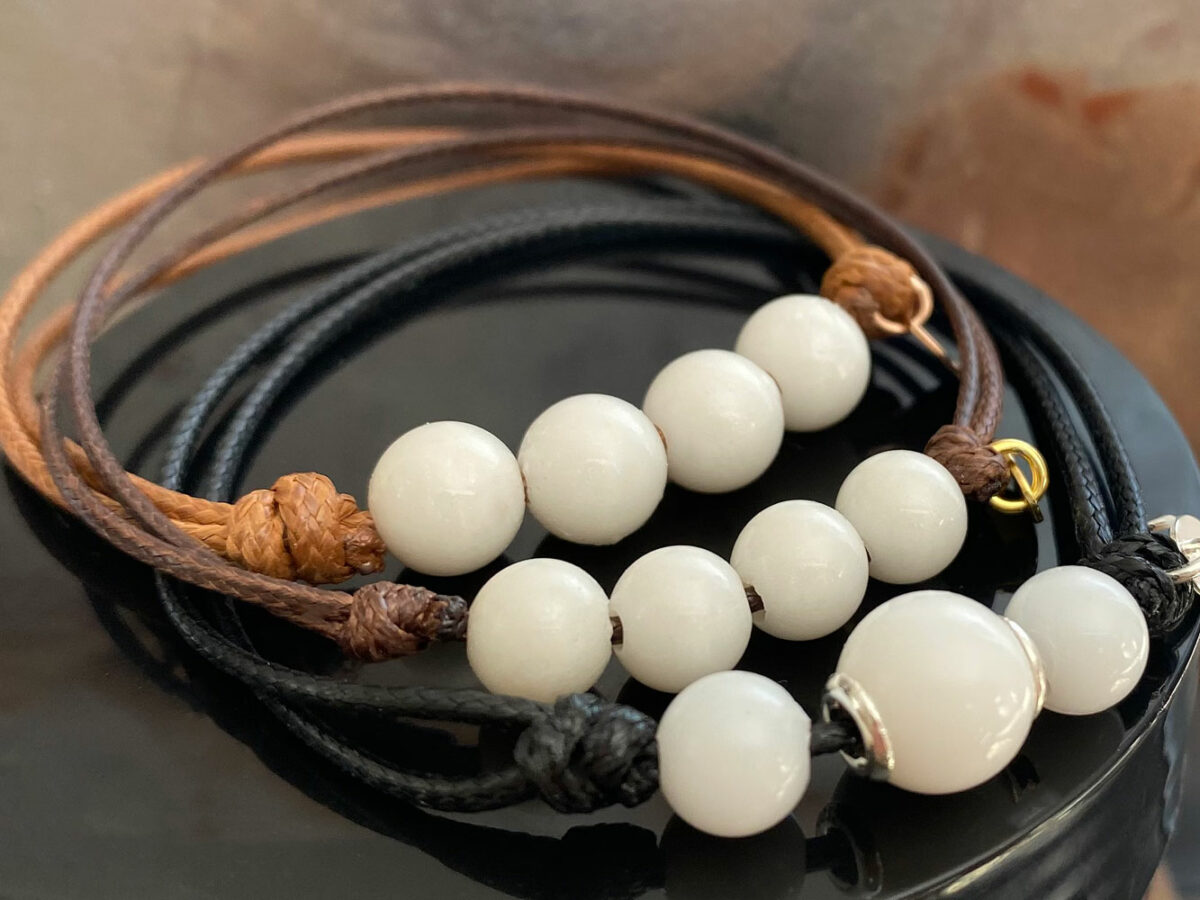 breastmilk three simple pearl bracelets made with breastmilk beads/pearls on a brown and black cord with silver cores on brown background from keepsakemom
