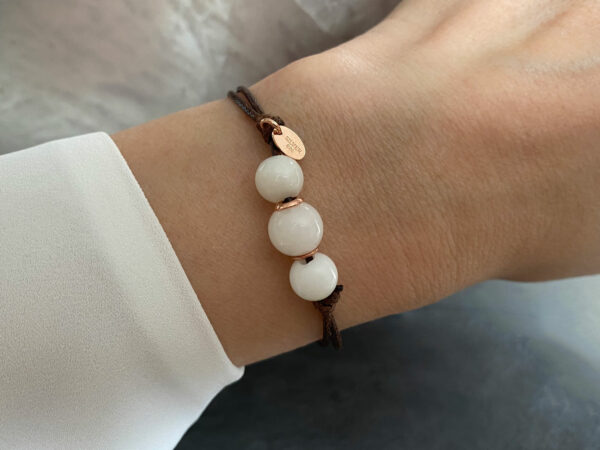 breastmilk three simple pearl made with breastmilk on a brown cord with rose gold cores and quality tag on a model wrist from keepsakemom