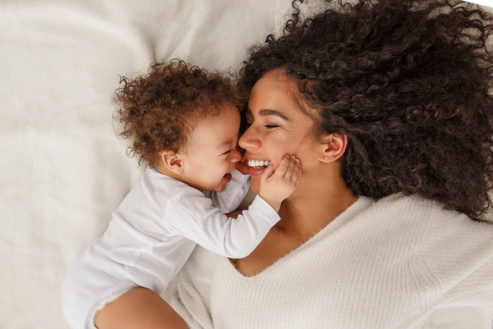 Happy mom and baby smiling in bed