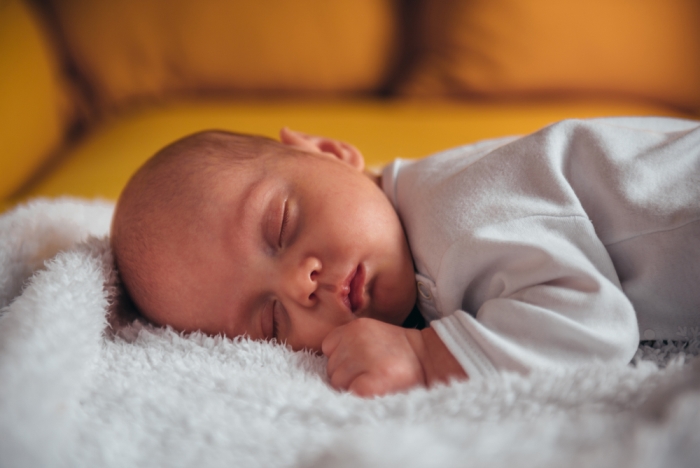 Newborn baby sleeping on a yellow couch