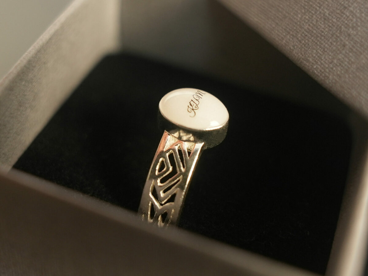 sterling silver with negatively spaced rectangular slits in a thick band with an oval-shaped breast milk stone with initials from KeepsakeMom