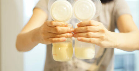 Mother holding two full bottles of expressed milk