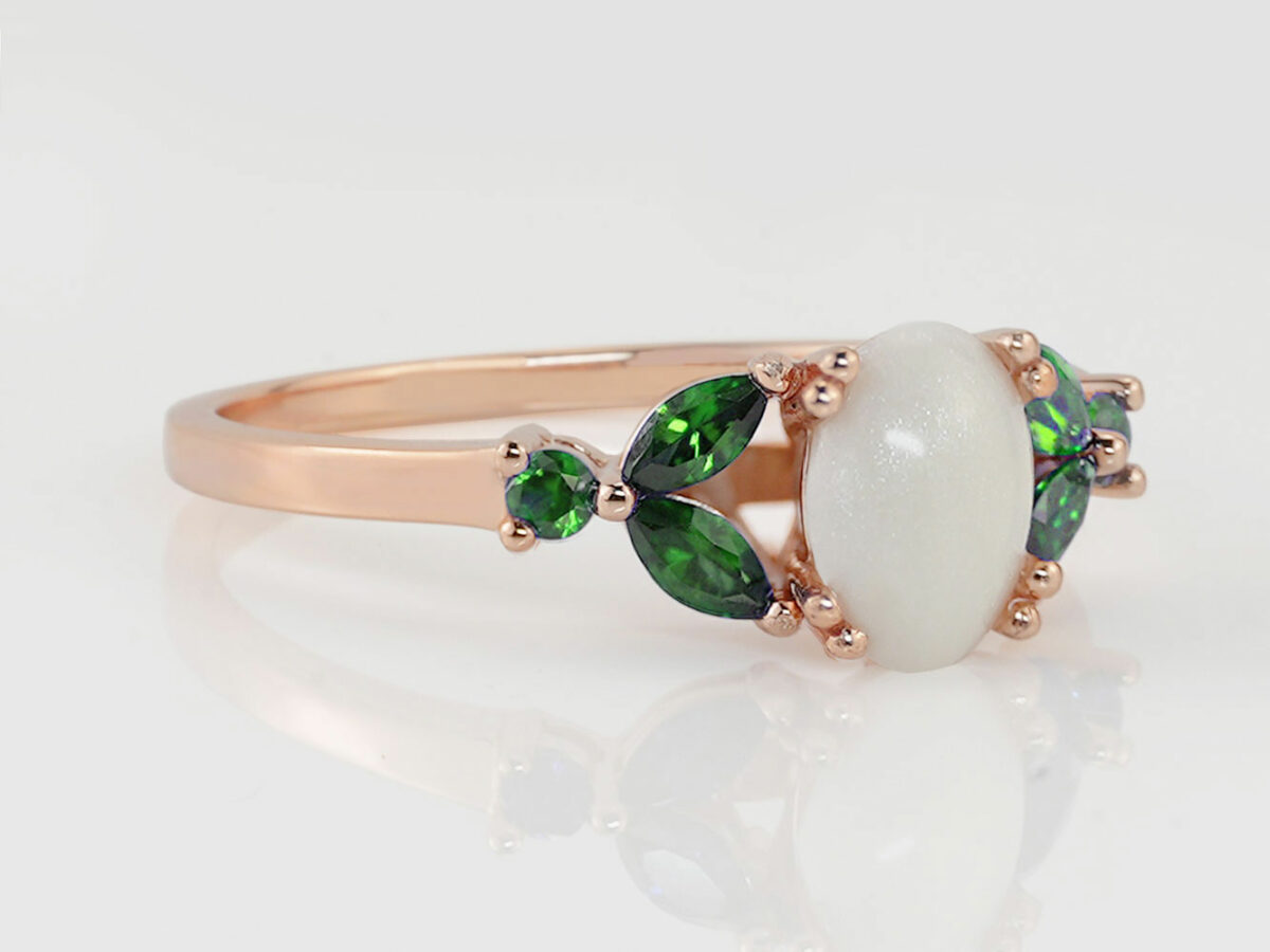 breast milk ring with oval stone and three emerald crystals or gems on each side in rose gold setting from KeepsakeMom