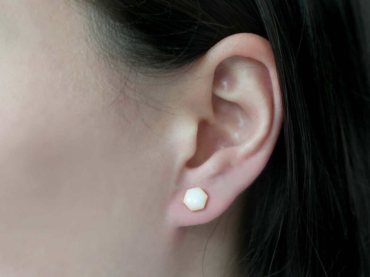breast milk jewelry yellow gold milk and honey earrings studded hexagon shape on white background from keepsakemom on brunette model ear
