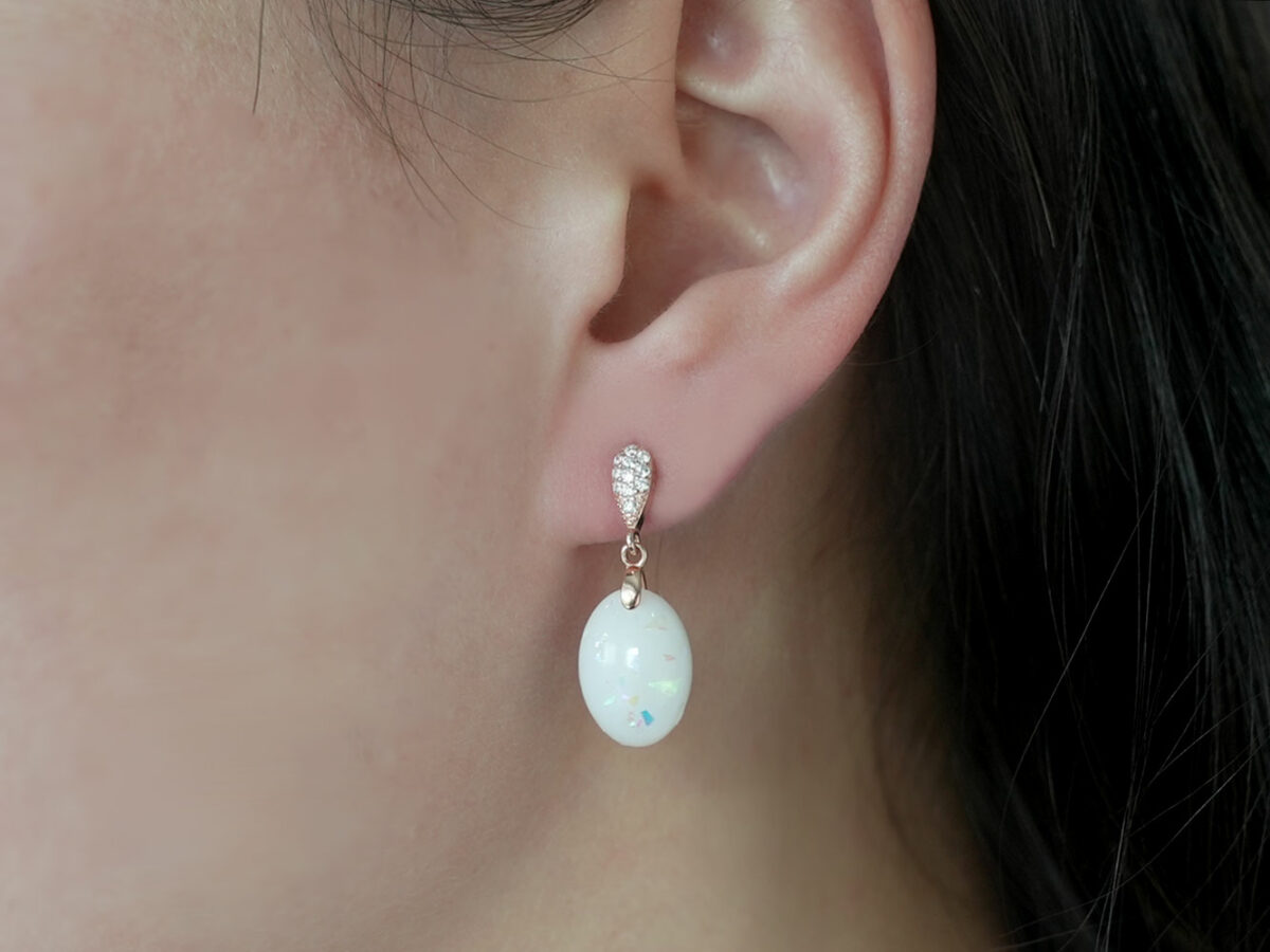 breastmilk jewelry earrings on a model ear from KeepsakeMom fancy dangle drop oval with opal flakes