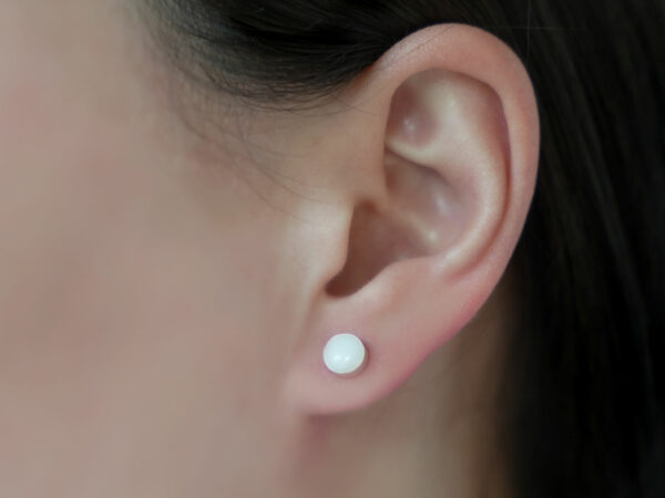 breastmilk jewelry earrings on a model ear from KeepsakeMom round simple studded