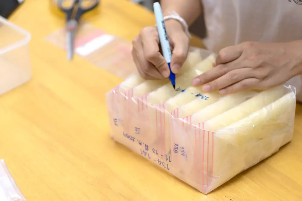 Woman writing dates on bags of frozen breast milk