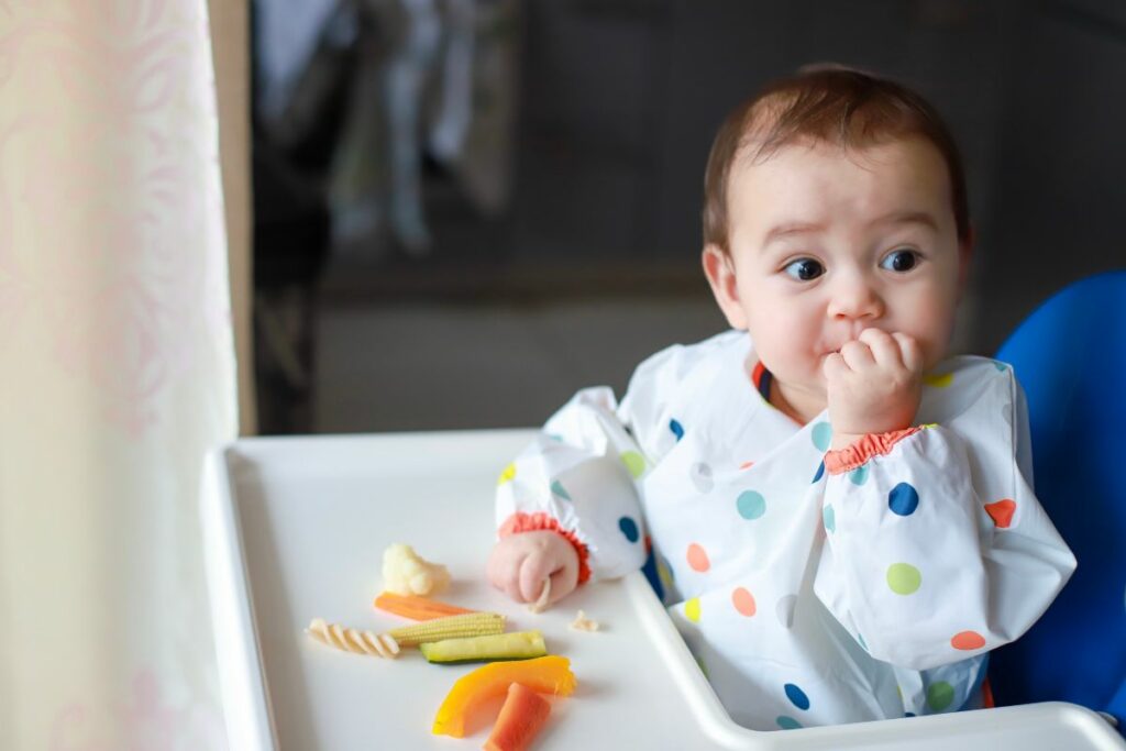 Boy eating by hands with finger food baby led weaning