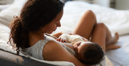 Mother breastfeeding her baby in bed