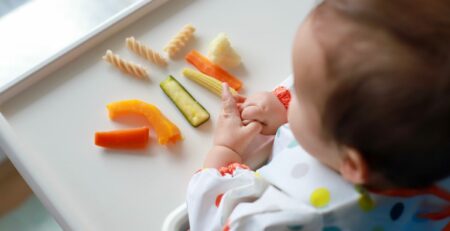 Top view of little boy holding food in his hands baby led weaning