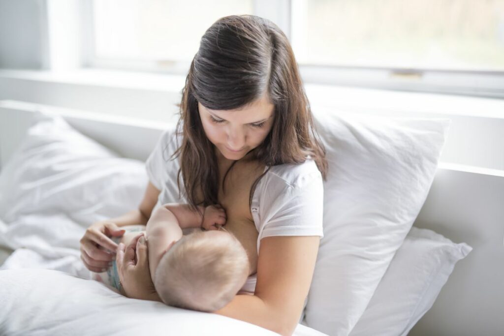 New mom breastfeeding her child in bed