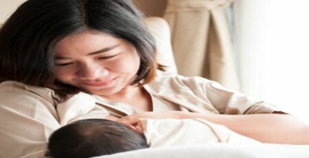 New mom in hospital kissing newborn son hand