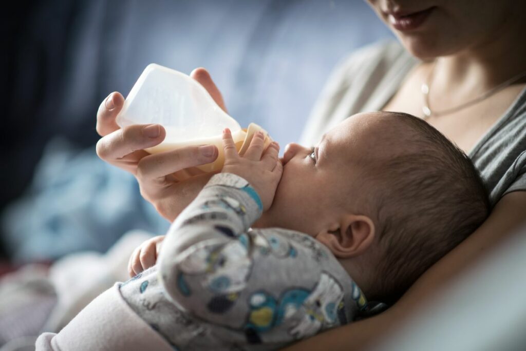 Mother feeding baby a bottle of formula and breast milk