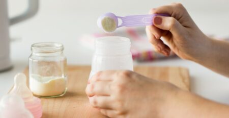 Mother making a bottle mixing formula and breast milk