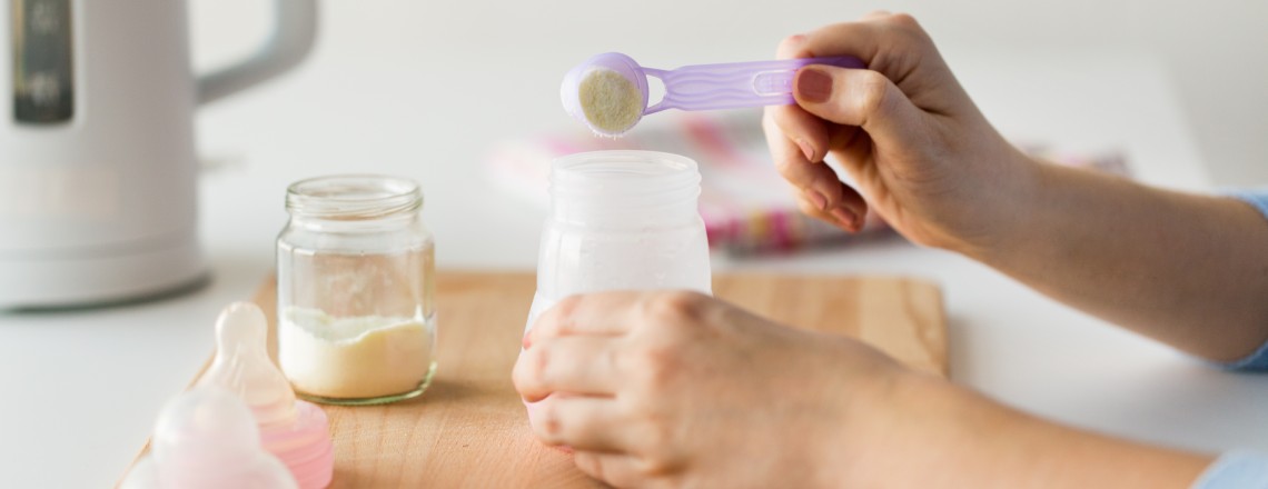 Mother making a bottle mixing formula and breast milk