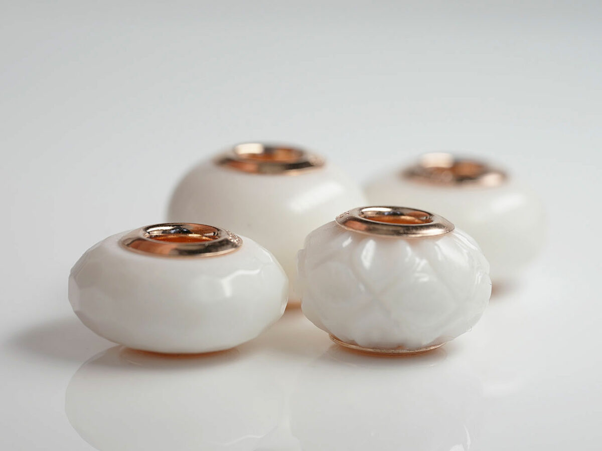 multiple four breastmilk jewelry beads different shapes and sizes with rose gold bead cores from keepsakemom on white background