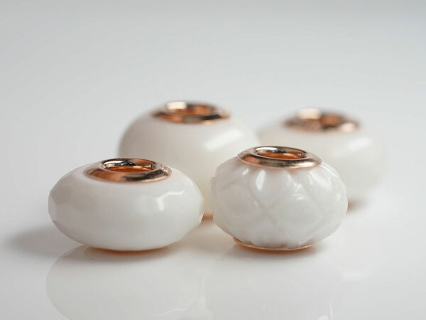 multiple four breastmilk jewelry beads different shapes and sizes with rose gold bead cores from keepsakemom on white background