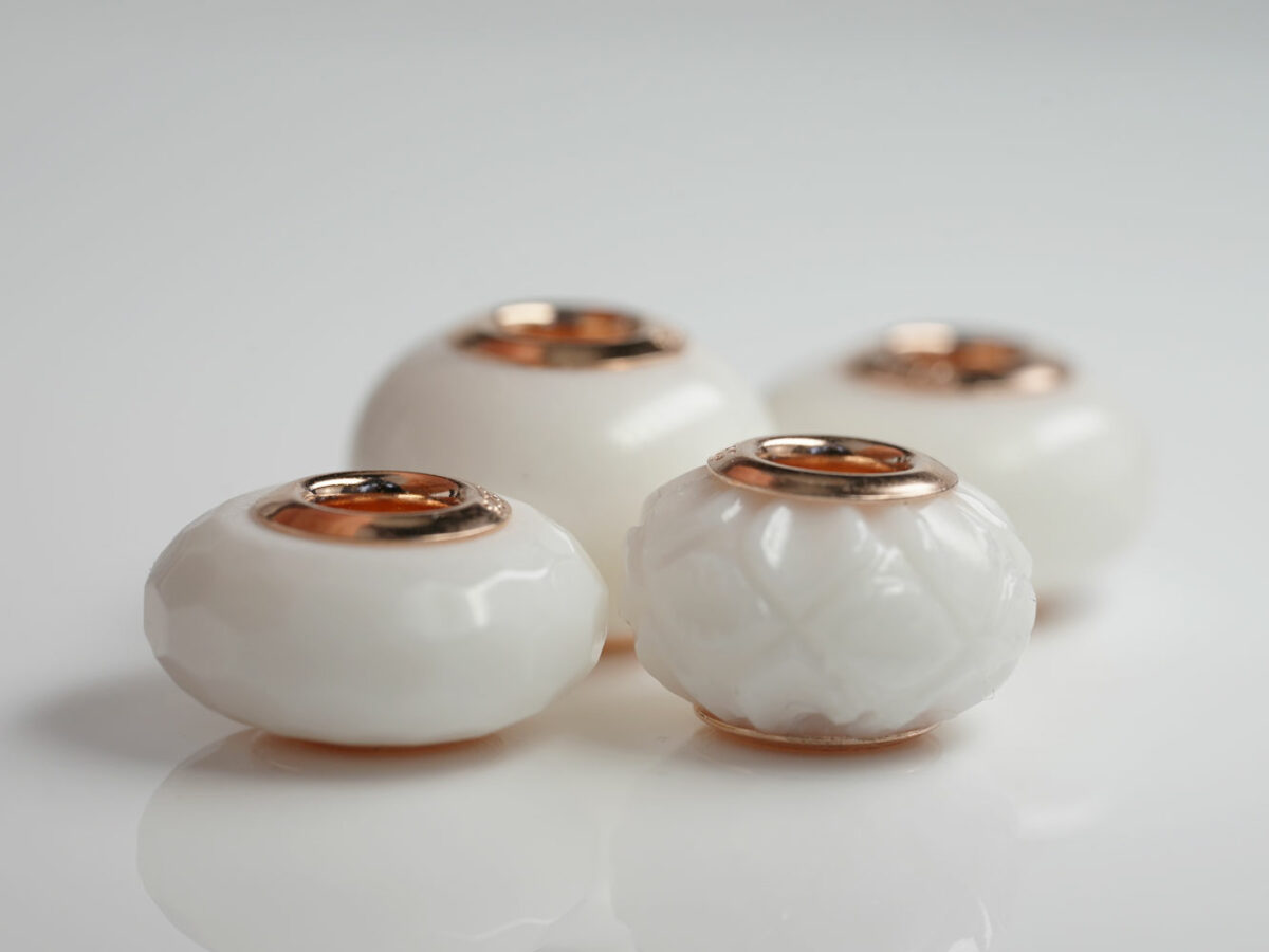 multiple four breastmilk jewelry beads different shapes and sizes with rose gold bead cores from keepsakemom on white background