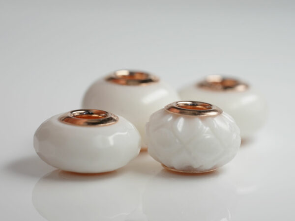 multiple four breastmilk jewelry beads different shapes and sizes with rose gold bead cores from keepsakemom on white background