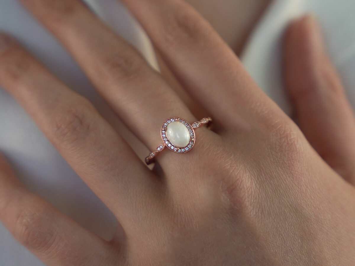 breastmilk jewelry ring oval stone fine band with crystals around the stone and the band fine ring rose gold KeepsakeMom model hand
