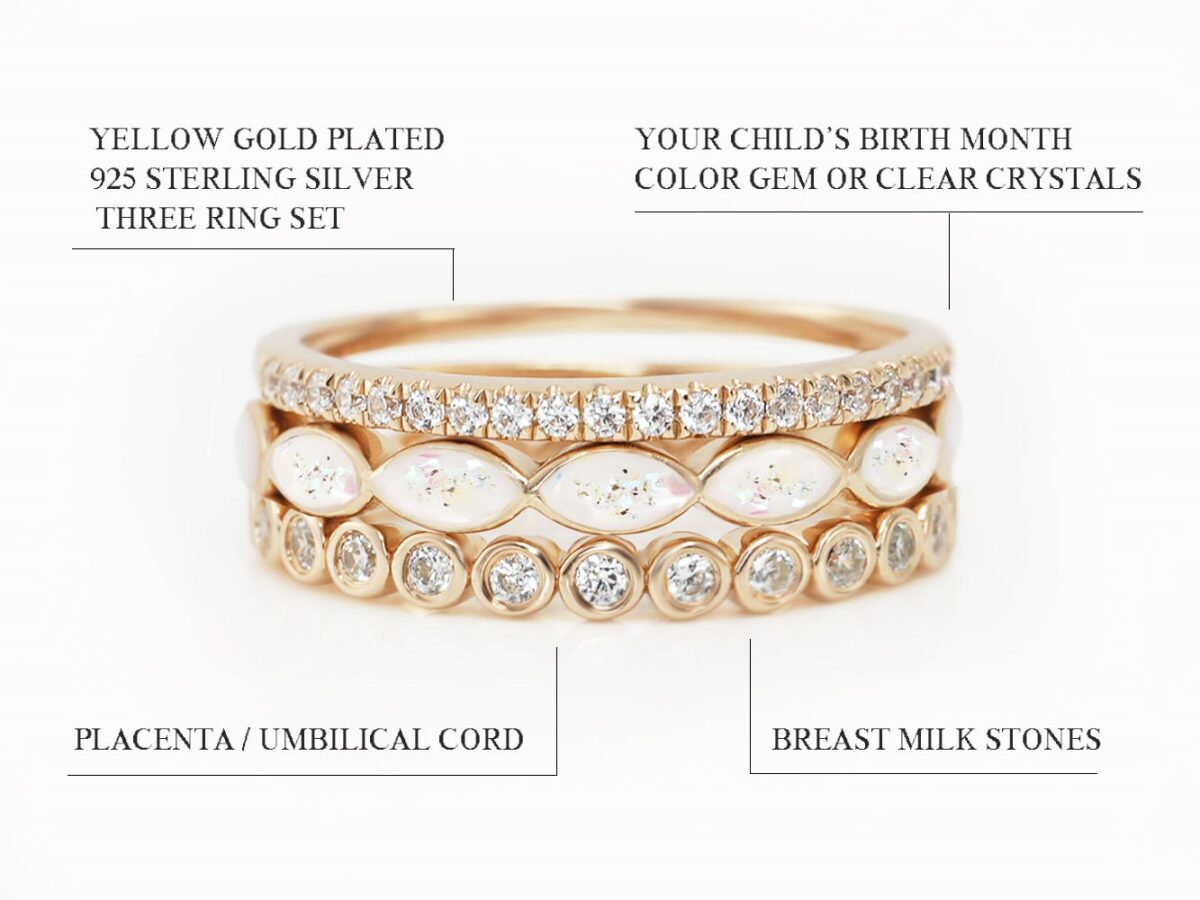 3 breastmilk sterling silver ring set in yellow gold plated setting with one ring filled with milk and opal flakes and placenta flakes and the top and bottom add-on ring clear crystals fine band diagram describing features on white background from keepsakemom
