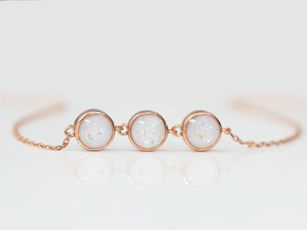 breastmilk jewelry luna three small discs bracelet rose gold setting from keepsakemom on white background with opal flakes