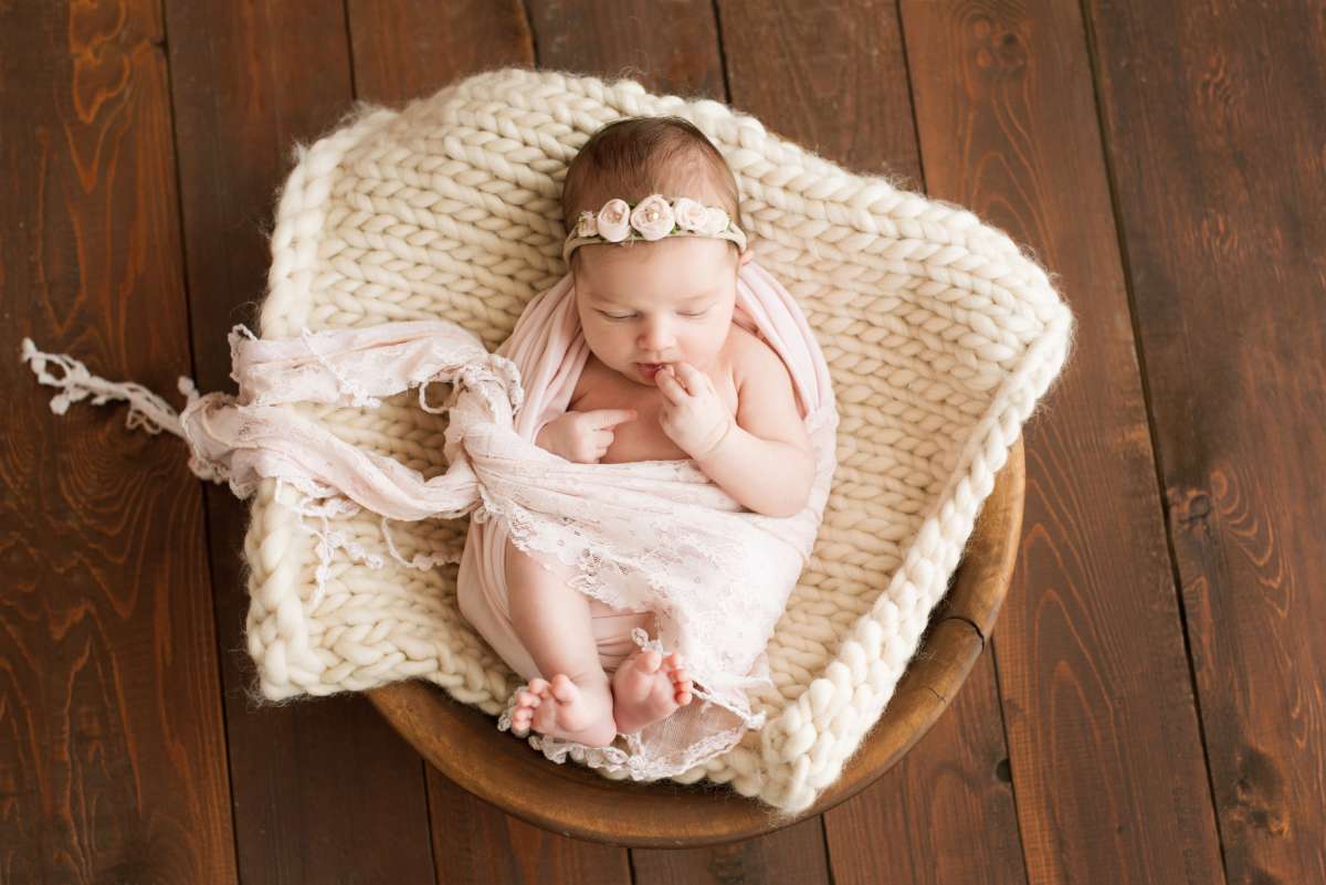 Newborn girl on a brown background in a cozy blanket in a basket