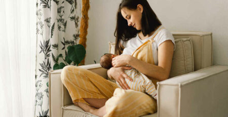 Portrait of mom and breastfeeding baby in living room