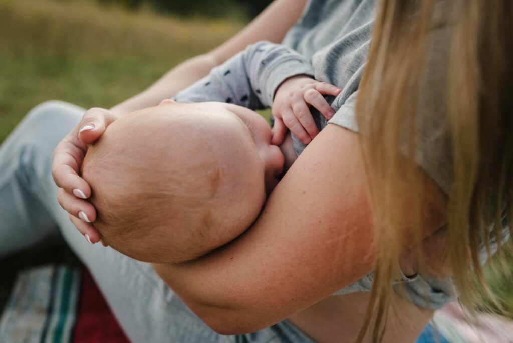 Mother breastfeeding baby in the park