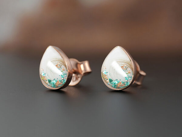 breastmilk pear teardrop shaped studded earrings from KeepsakeMom sterling silver on brown background with green flakes and locks of hair
